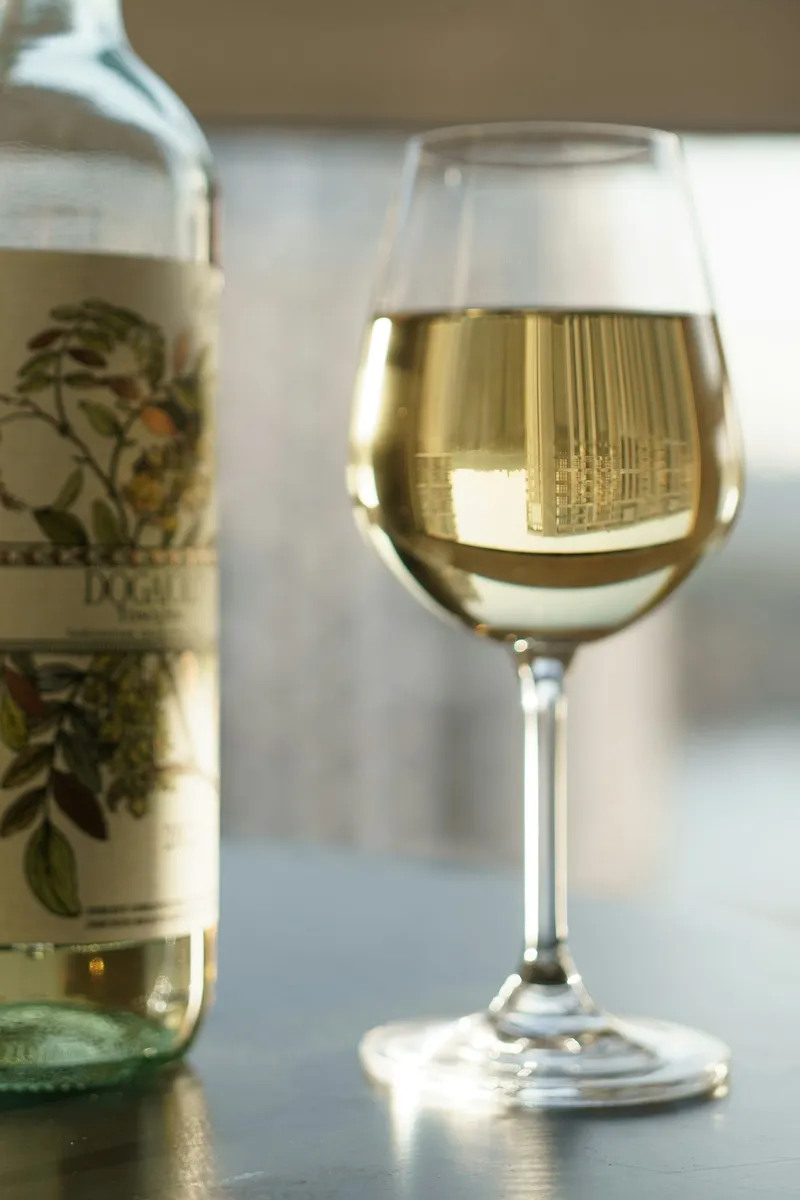 A bottle and a glass of white wine on a table